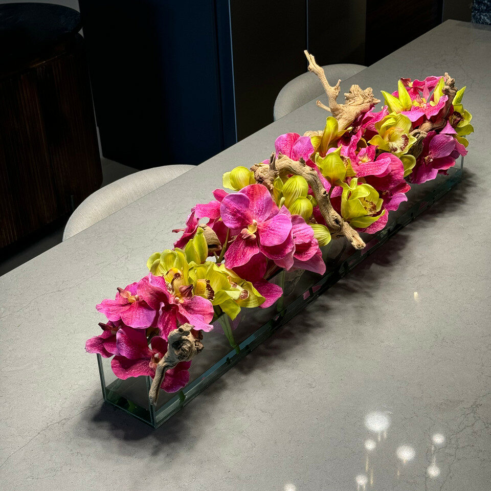 Moderne Hausvase aus Glas mit rosa Vanda-Orchideen und grünen Cymbidien